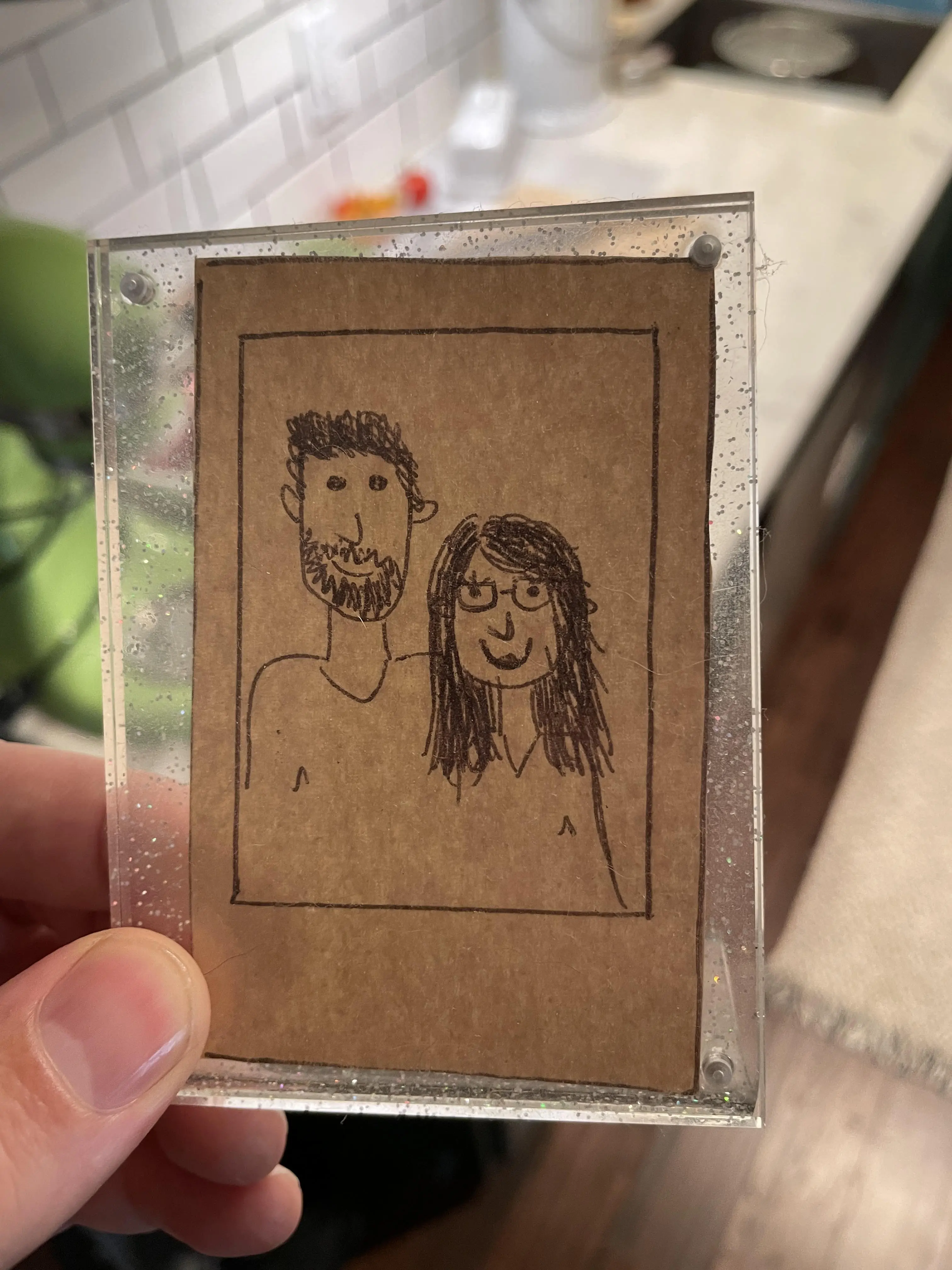 A drawn picture of a couple held up by a left hand